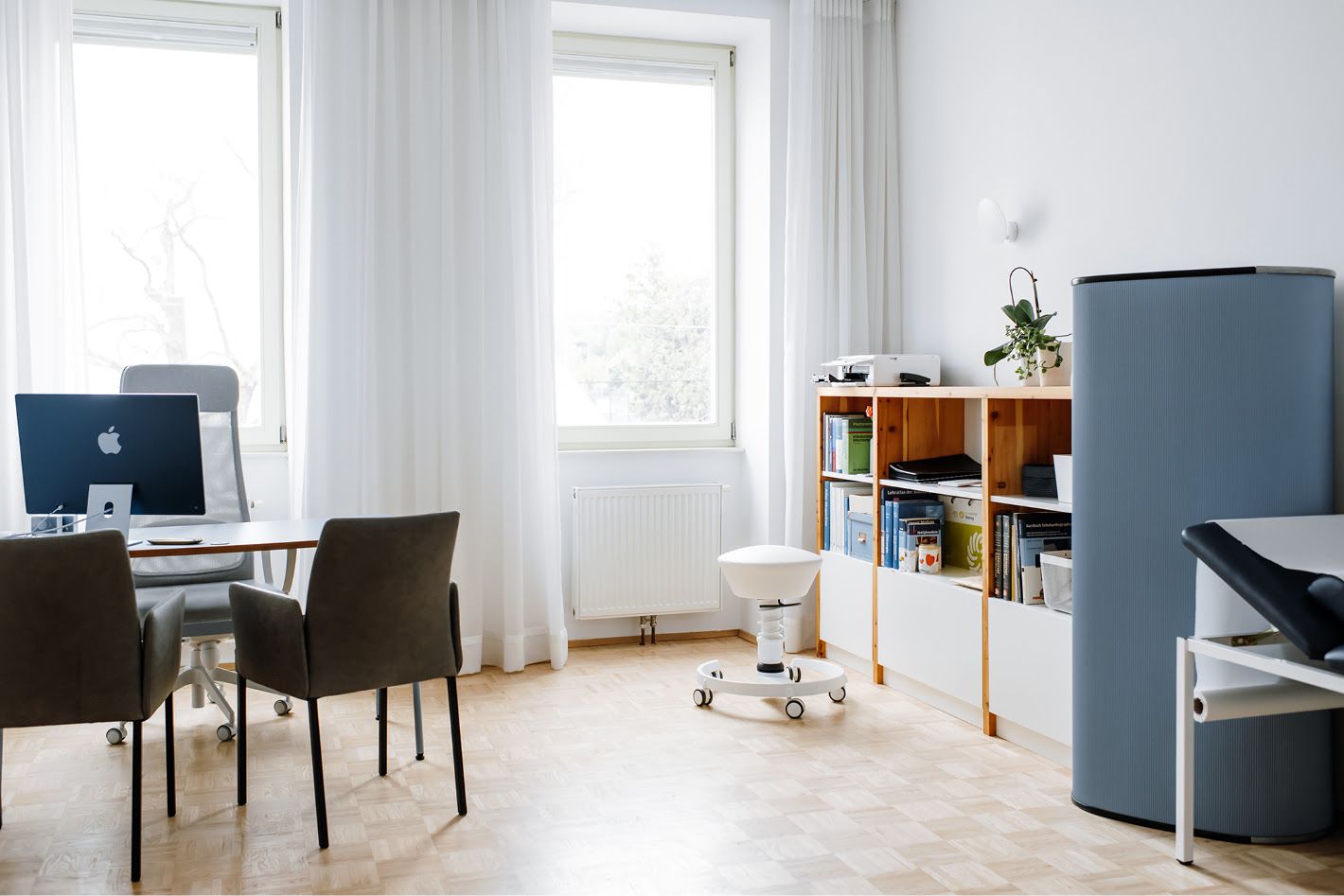 Praxisraum mit Schreibtisch und Regal