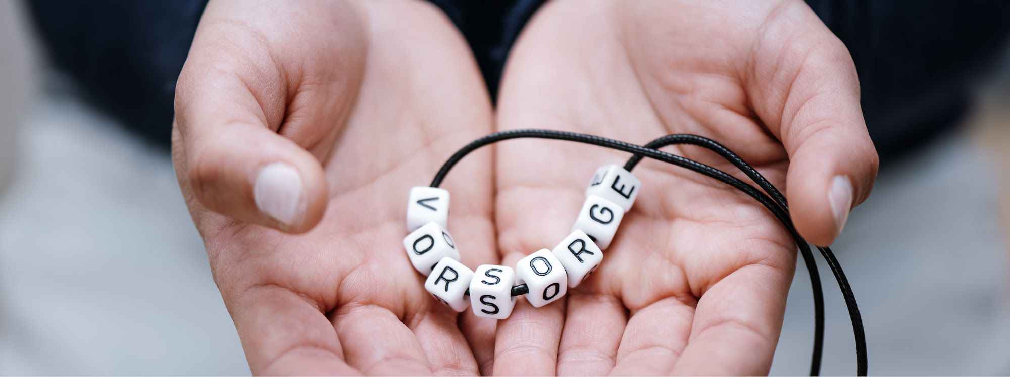 Hände halten eine Kette mit den Buchstaben Vorsorge