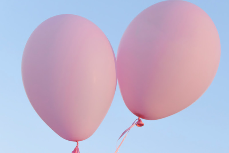 Zwei rosa Luftballons vor blauem Himmel